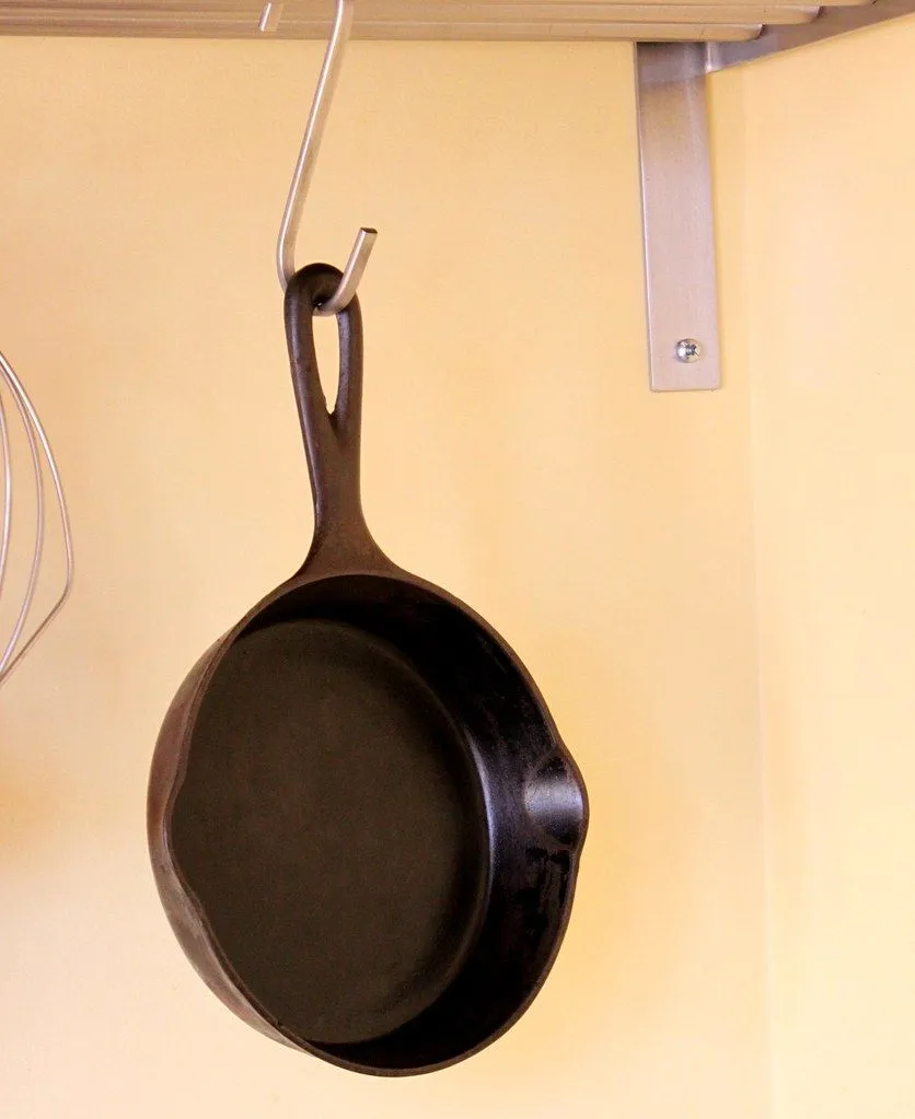 A seasoned cast iron frying pan hanging from a hook in a kitchen