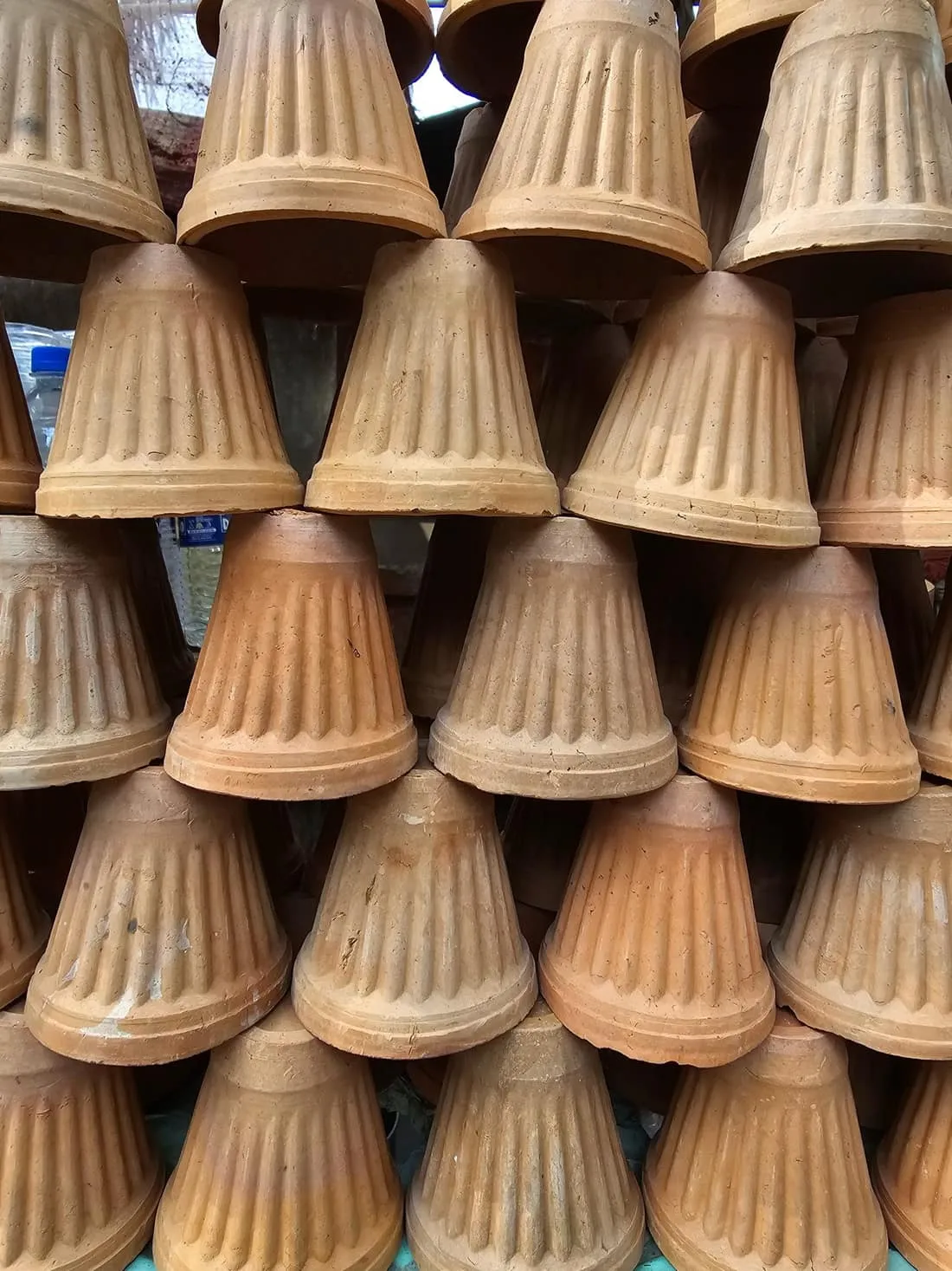 A tall stack of unglazed clay pots in a market