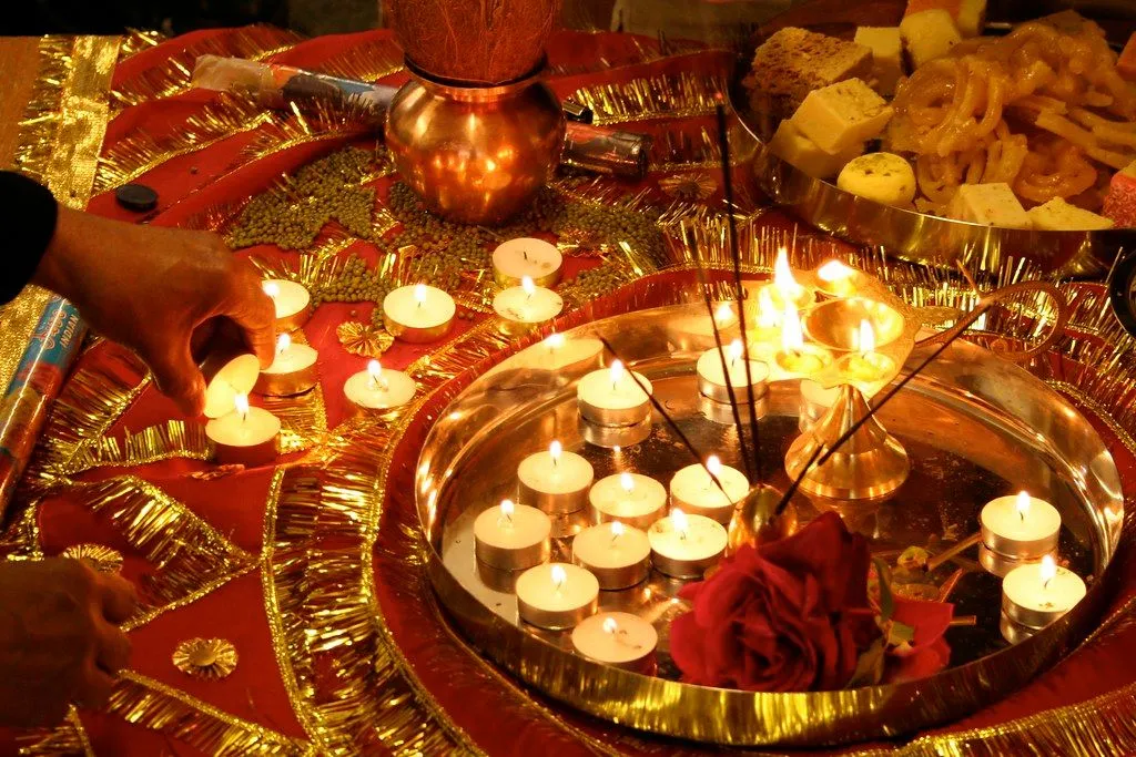 Brass thali with lit tealights, sweets and a kalash during Diwali puja