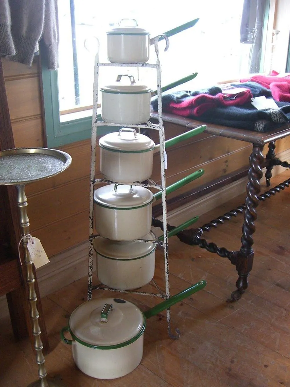 A stack of cream and green enamel saucepans with lids on a rack
