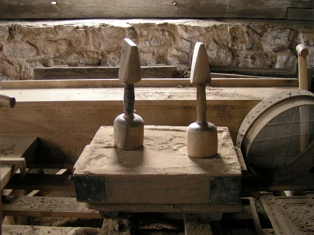 A wooden sand mould box with two hand rammers resting on top of it