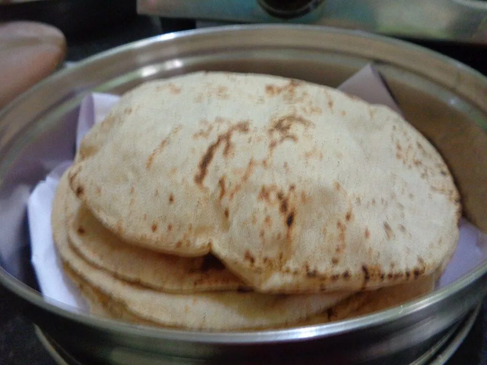 A stack of freshly made rotis in a steel box