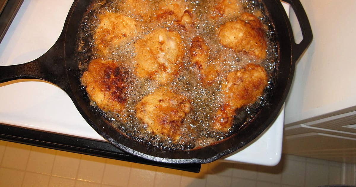 Golden pieces shallow-frying and bubbling in a cast iron fry pan on the stove