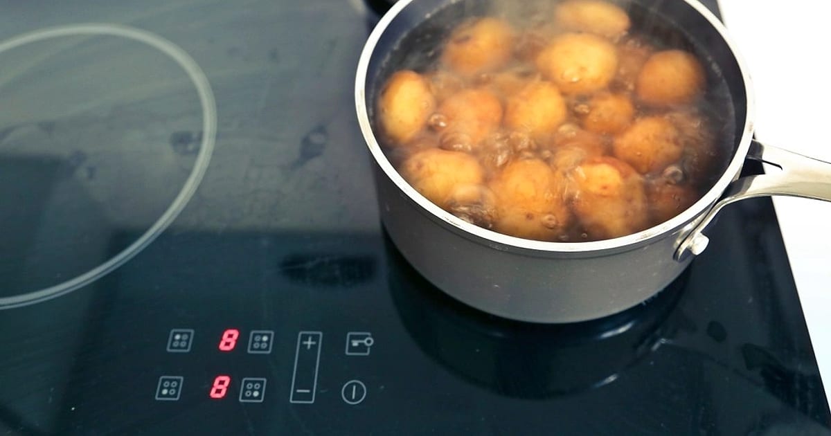 Potatoes boiling in a pan on an induction hob, its red power-level digits lit