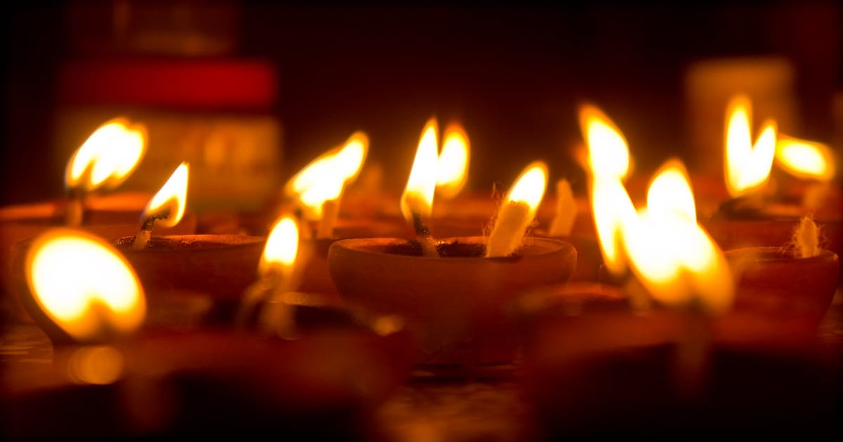 Rows of clay diyas glowing in the dark for Diwali