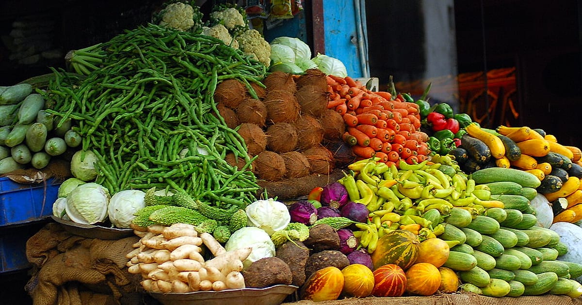A colourful Indian vegetable stall piled with beans, carrots, cucumbers, gourds, cabbage and coconuts